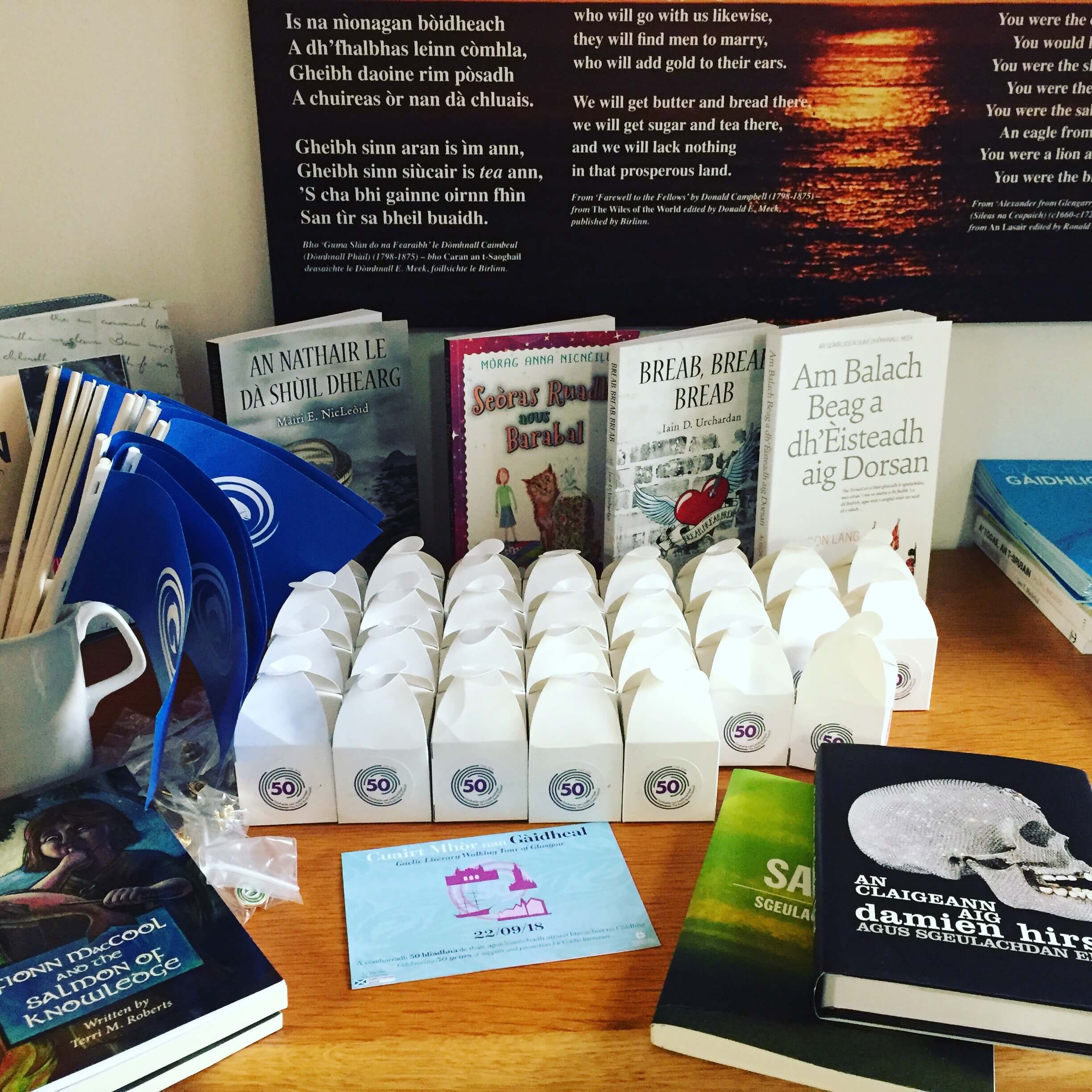 Still life with Gaelic books, Nova Scotia Gaelic flags, and Scottish tablet (in the boxes) at the Gaelic Books Council